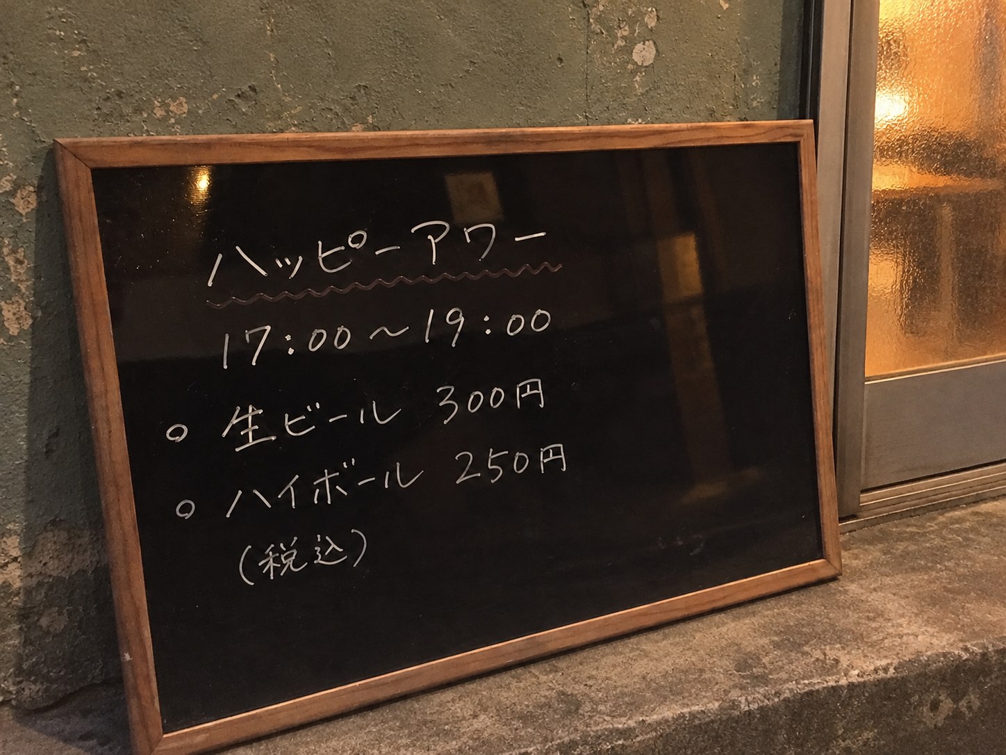 A happy hour board at an izakaya listing discounted highballs and draft beer with the times