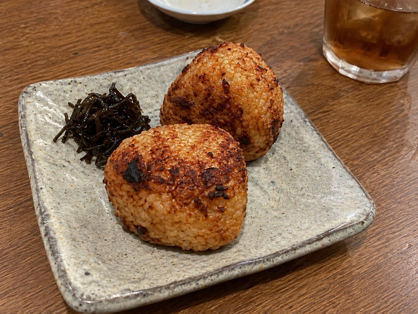 Two grilled rice balls with a golden soy-sauce crust on a small plate